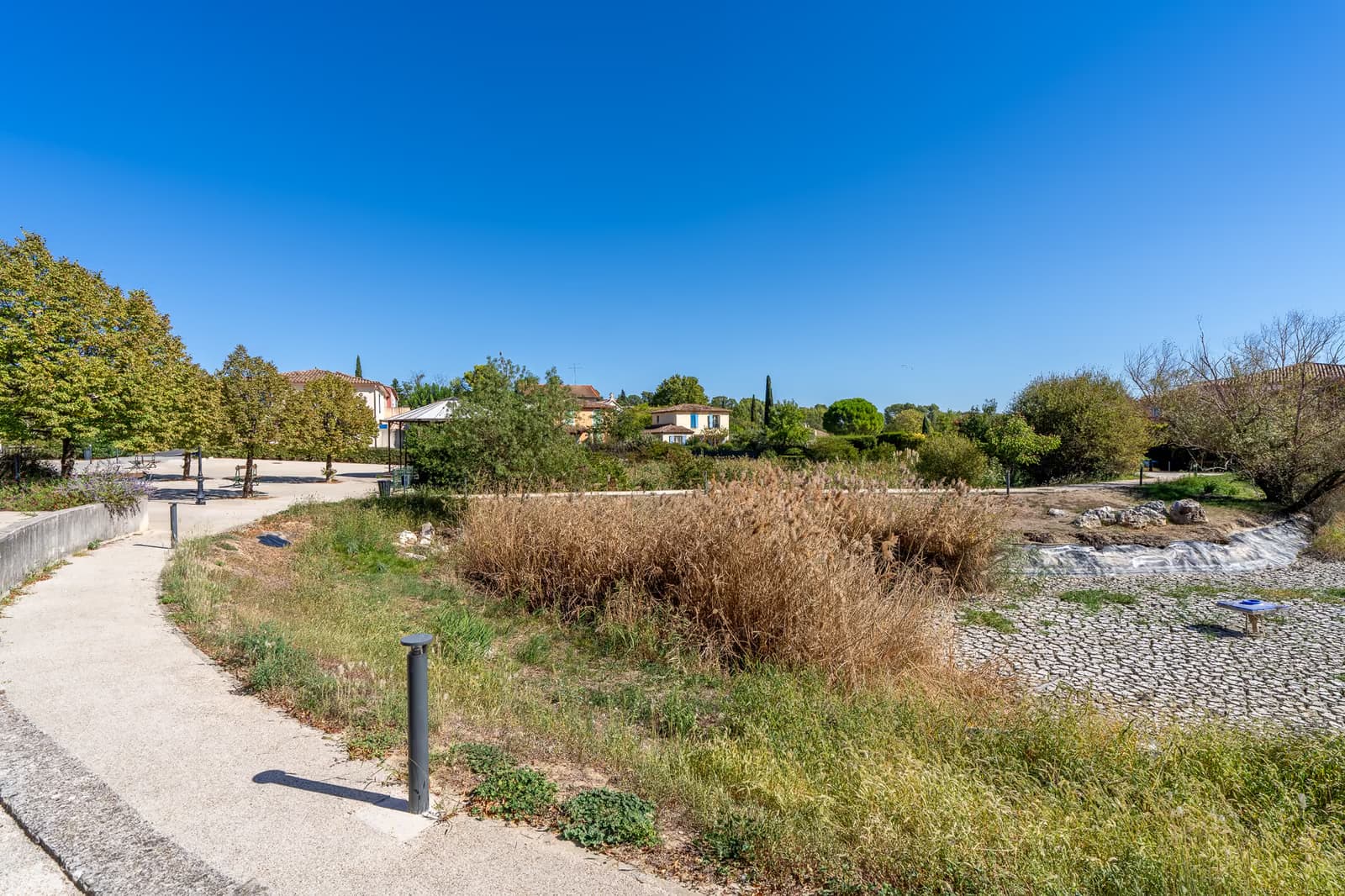 Bassin paysager planté de roseaux et cheminement piéton au centre du village de Saint-Clément-de-Rivière