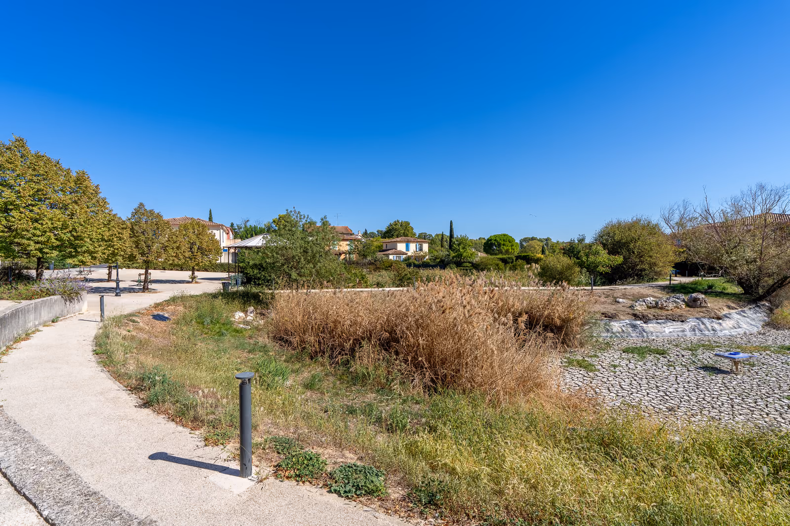 Bassin paysager planté de roseaux et cheminement piéton au centre du village de Saint-Clément-de-Rivière